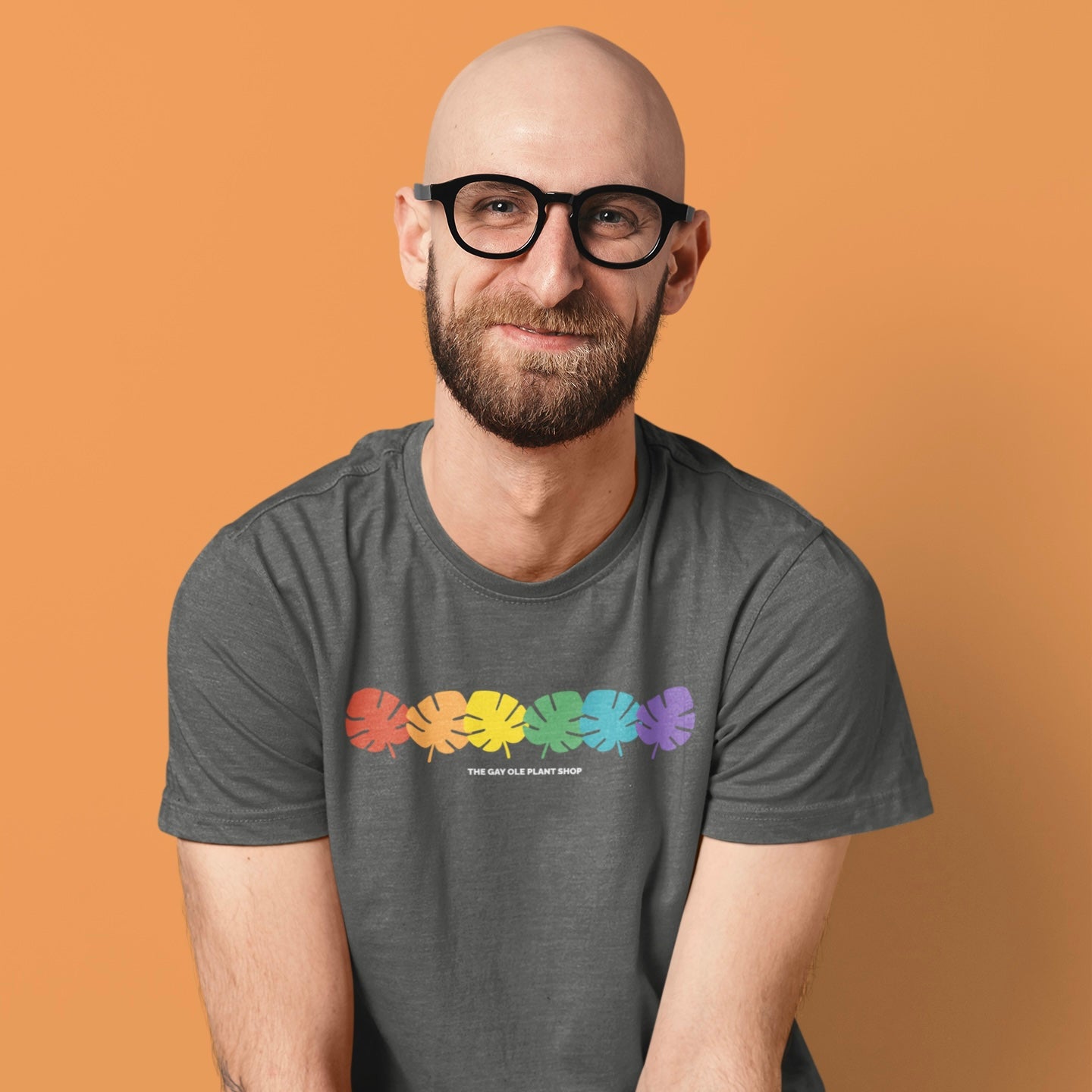 Man wearing a gray t-shirt with rainbow leaf design on an orange background