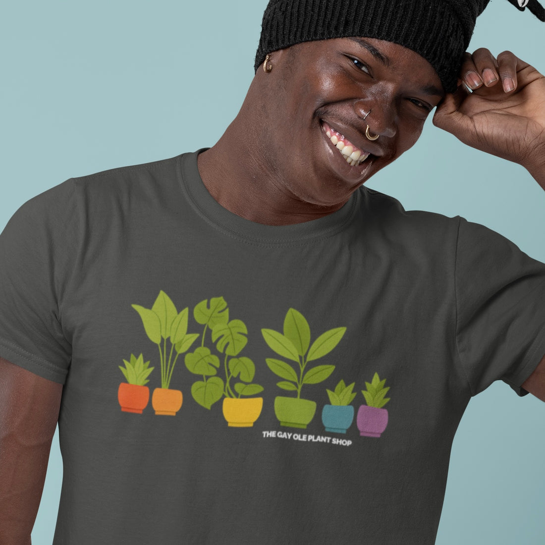 Person wearing a t-shirt with plant design and text, smiling against a light blue background