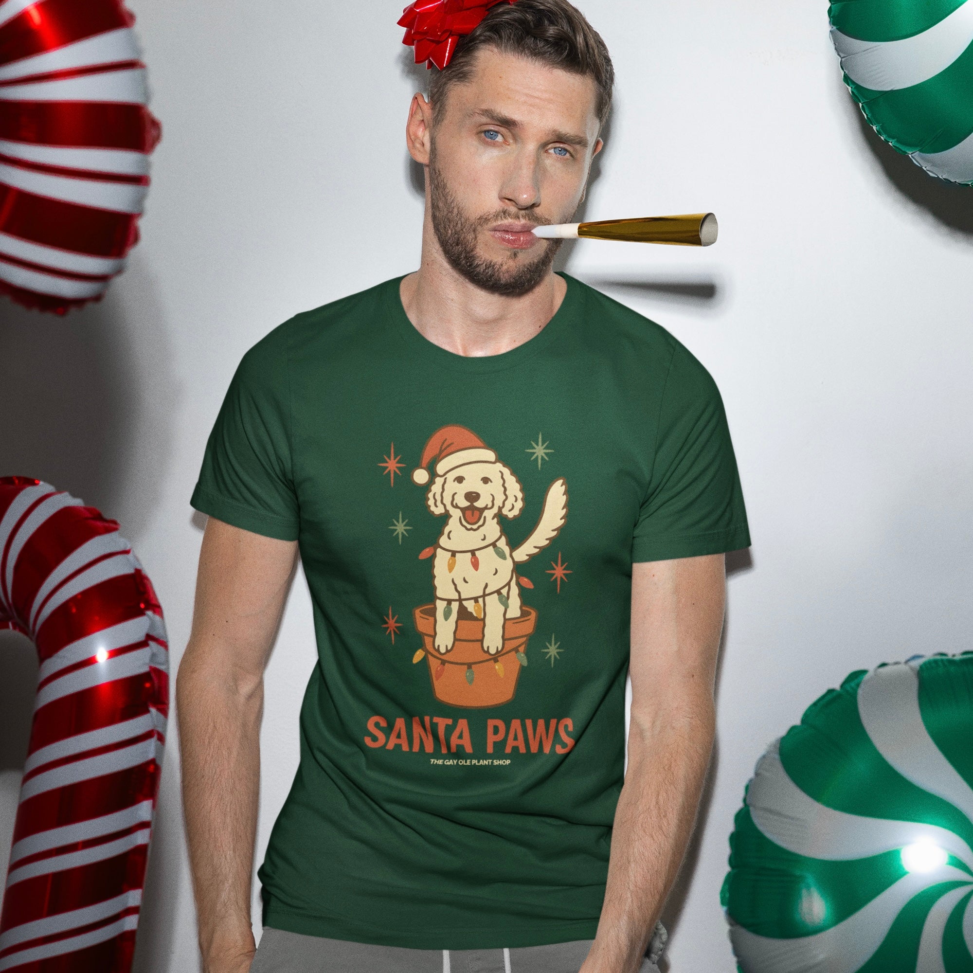 Man wearing a green t-shirt with a Christmas-themed design, surrounded by festive balloons.